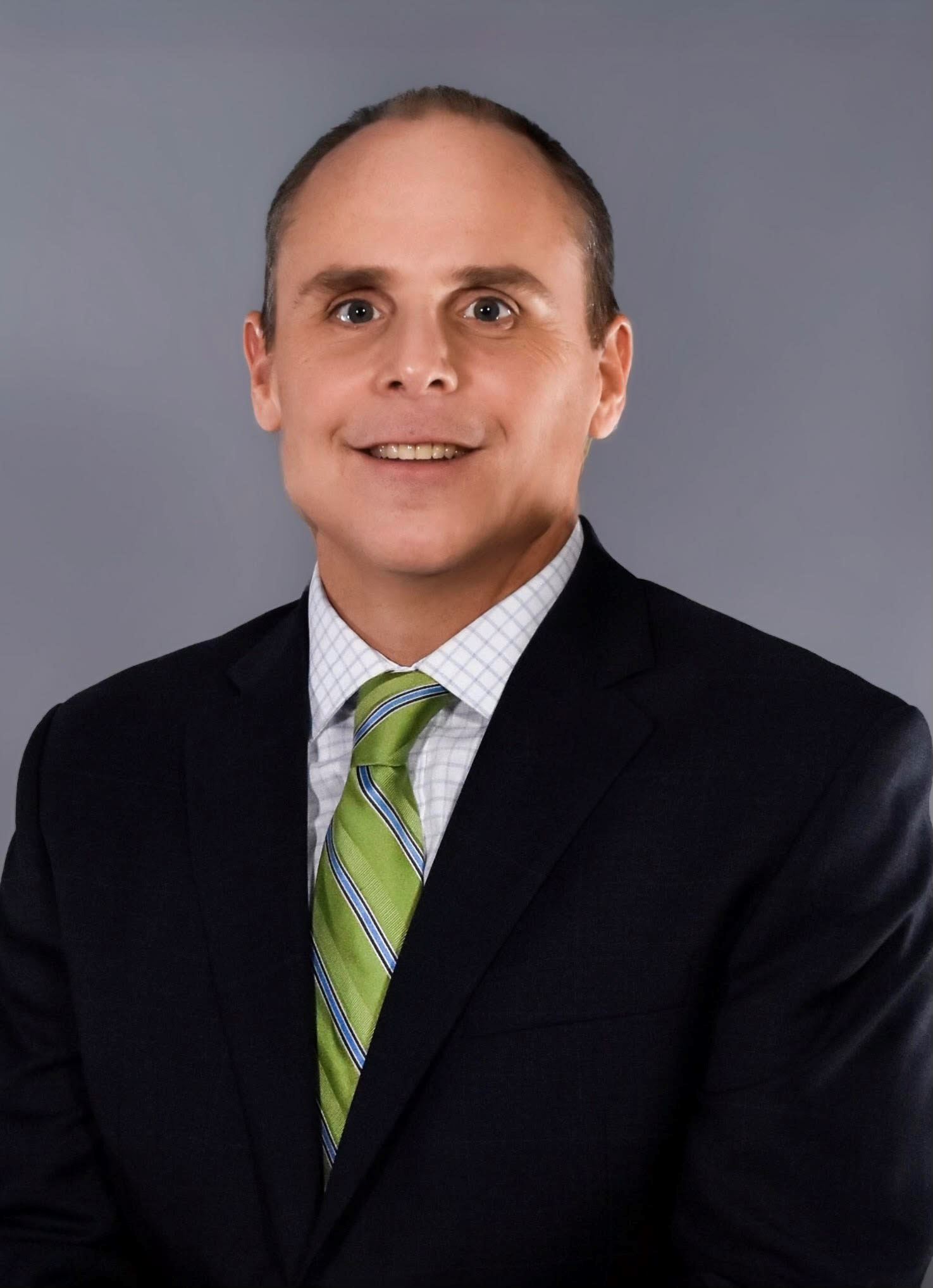 Headshot of a man wearing a green tie.