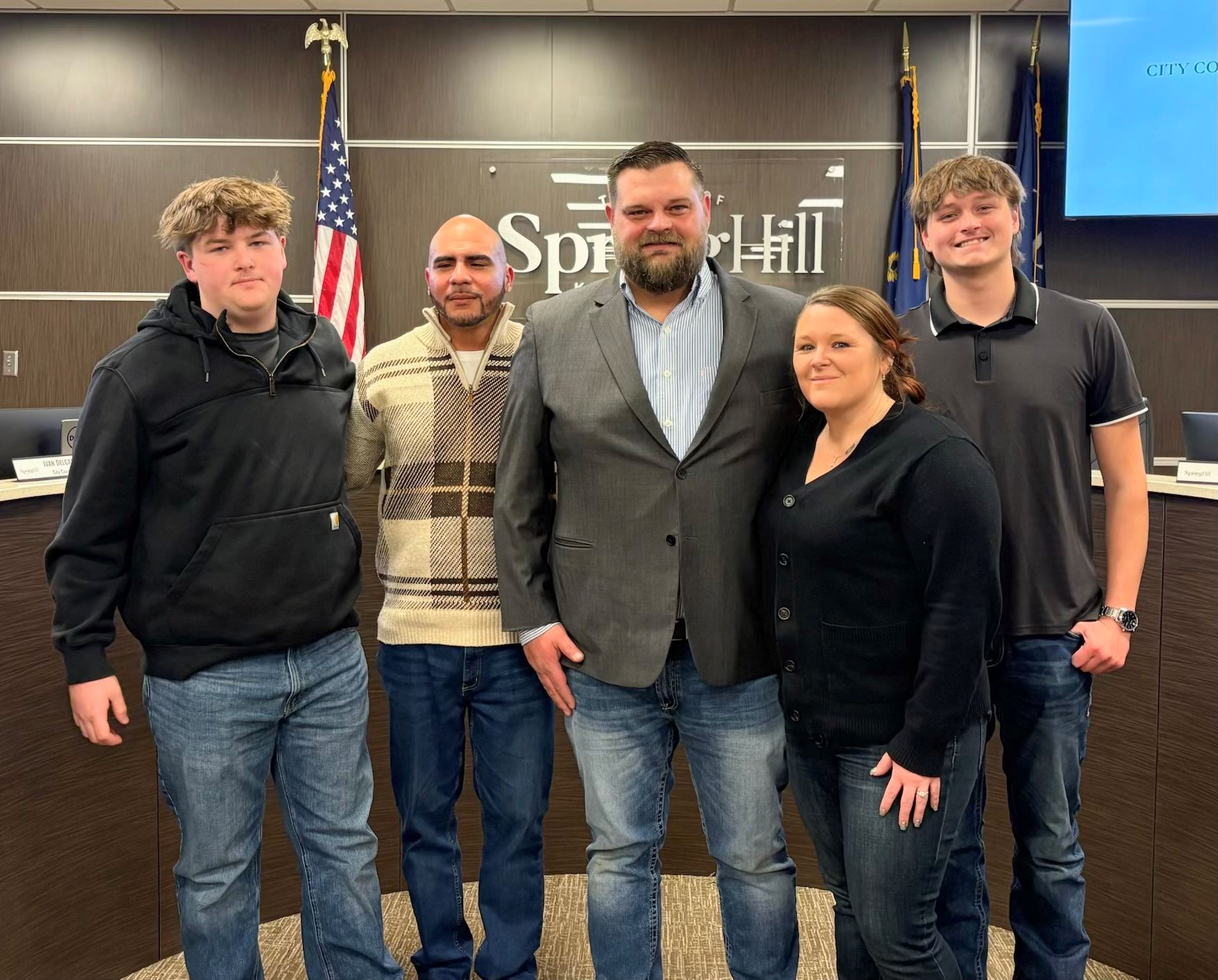 A man poses with his family inside the City Council chambers.